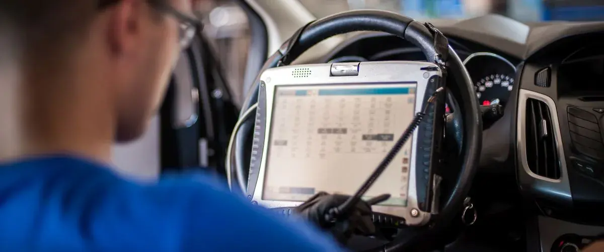 Diagnosegerät am Lenkrad eines Fahrzeugs, ein Techniker liest die Daten ab