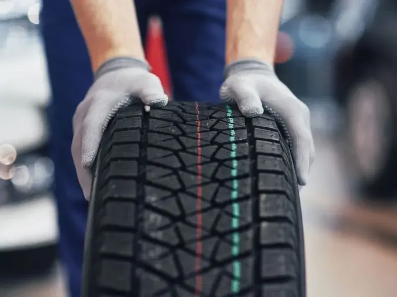 Monteur trägt einen Reifen durch die Werkstatt