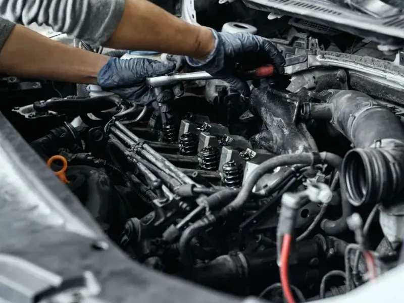 Hände mit Ratsche bei einer Reparatur im geöffneten Motorraum